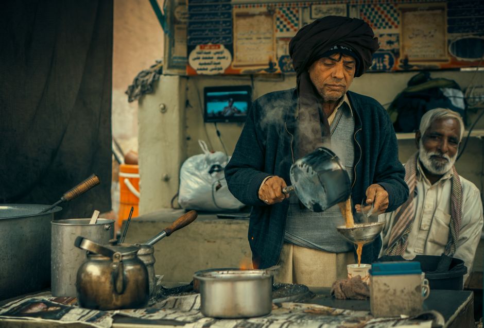 A street vendor in Faisalabad, Pakistan making traditional tea with steam rising.