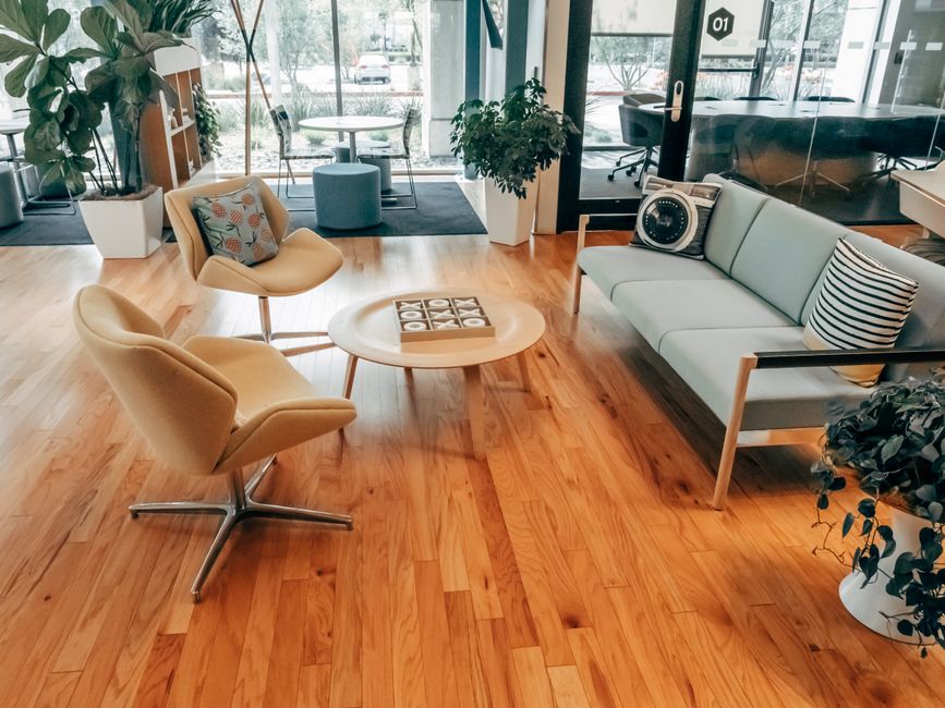 A bright and inviting office lounge with contemporary furniture and wooden flooring.