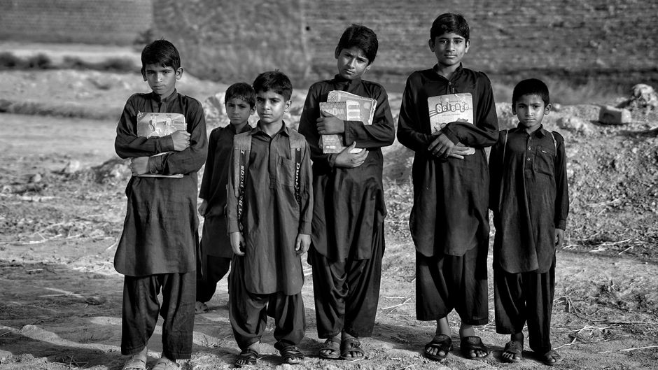Black and white image of boys holding books, highlighting education.