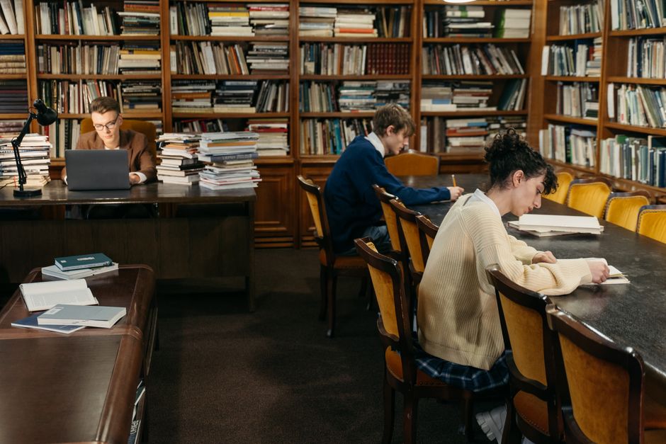 Students engaged in study inside a peaceful library with bookshelves.