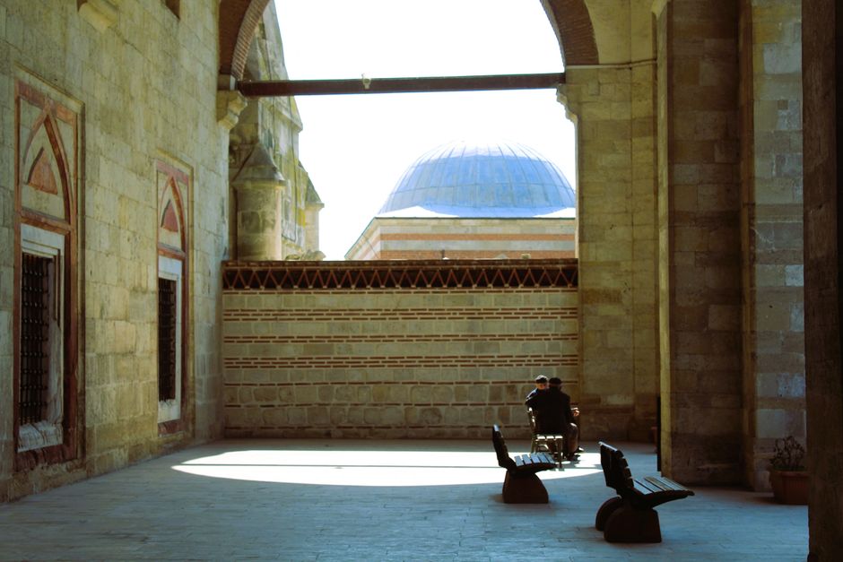 A serene view of a historic mosque courtyard in Edirne, Türkiye, with a domed roof in the background.