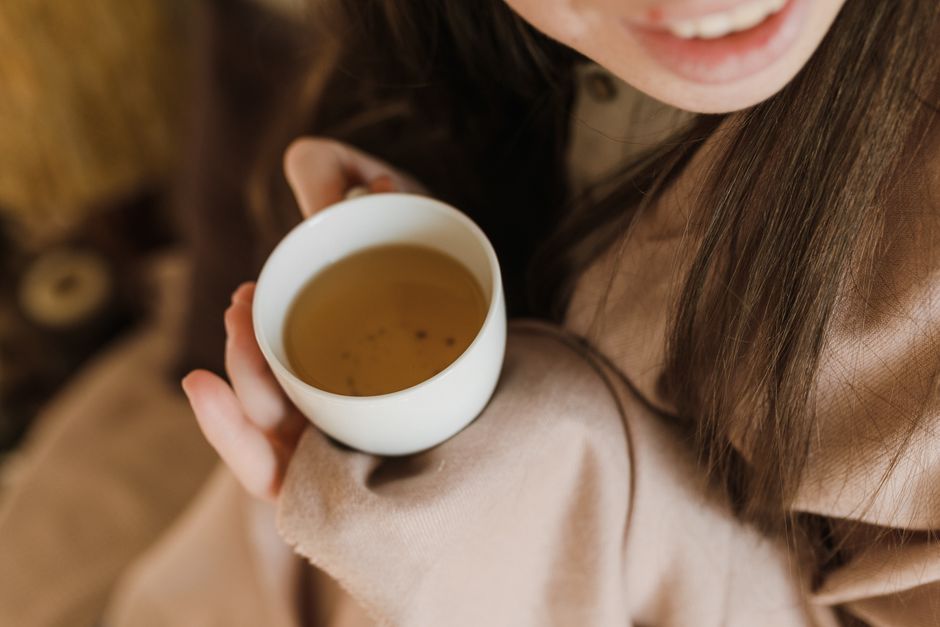 A person enjoying a relaxing moment with a warm cup of tea indoors.