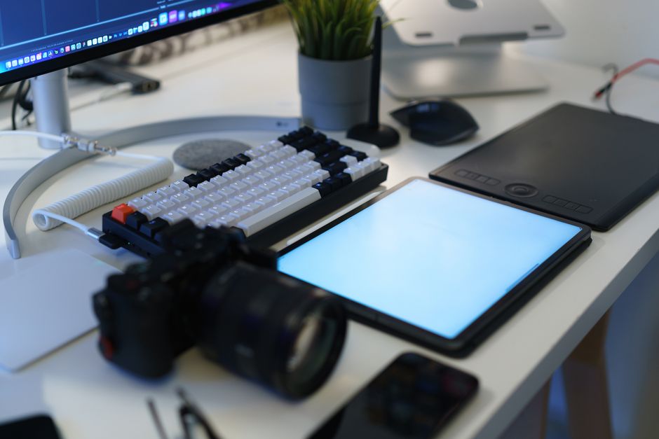 A modern home office with photography equipment, graphic tablet, and ergonomic keyboard.