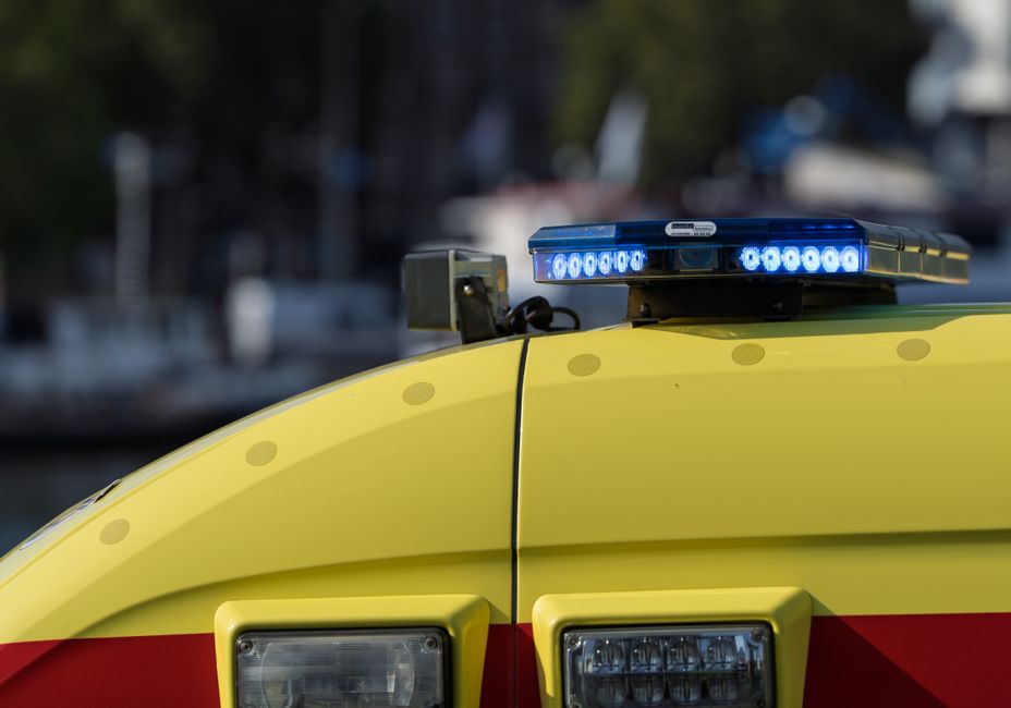 Focused shot of an ambulance roof displaying a blue flashing emergency light, ideal for emergency service themes.