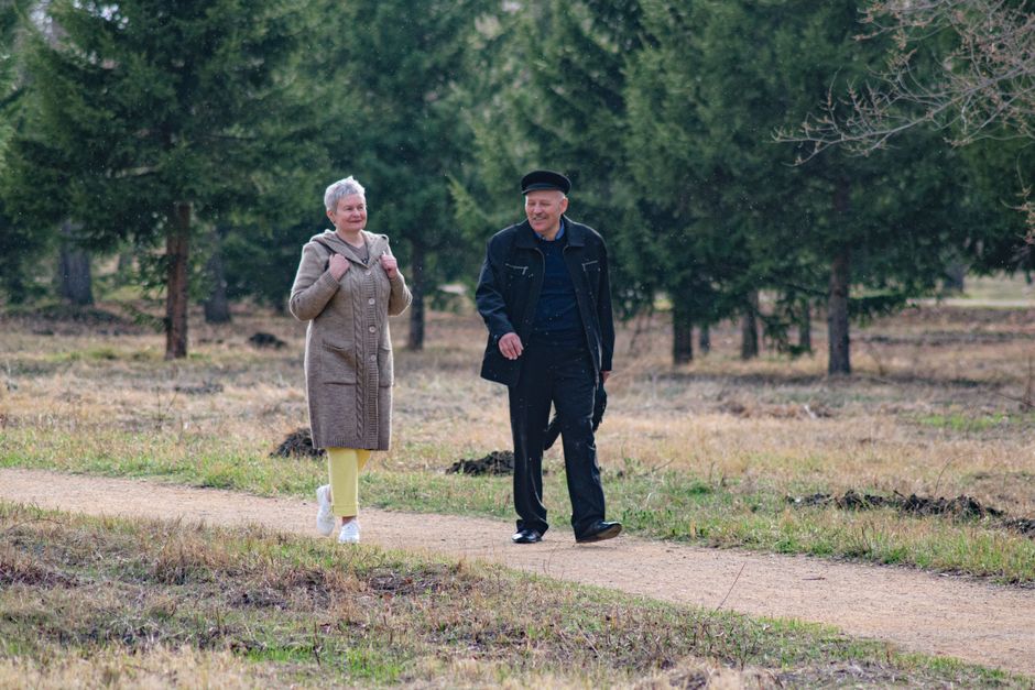 Happy senior couple strolling along a park path on a pleasant spring day.