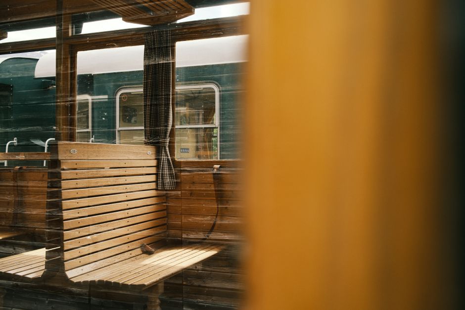 Classic wooden bench inside a vintage train with view of adjacent carriage.
