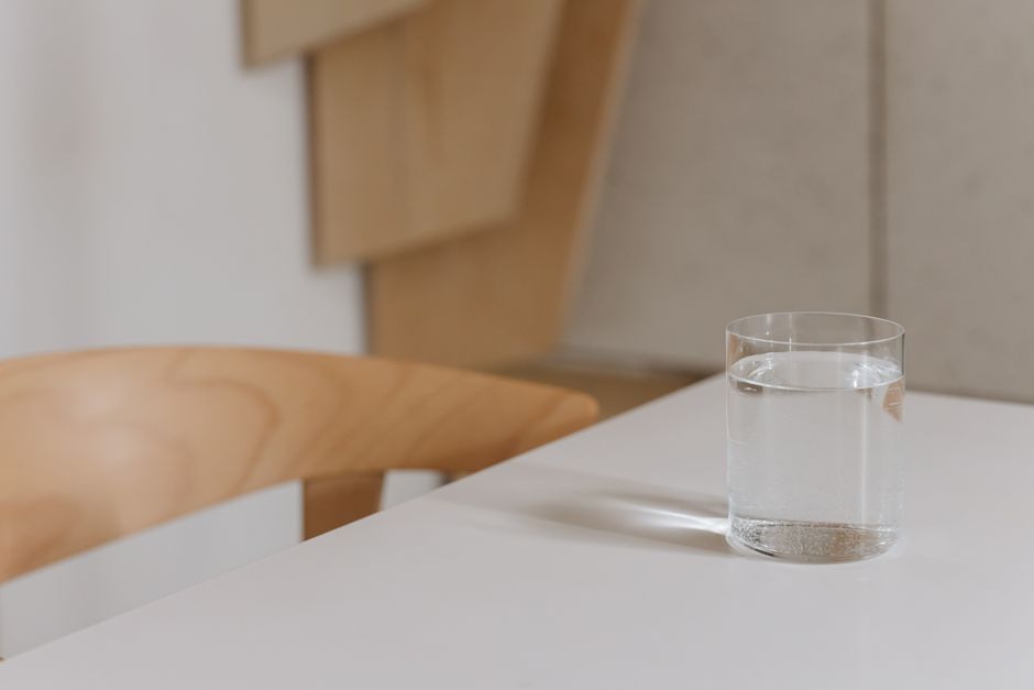 Simple and elegant composition of a water glass on a modern wooden table indoors.