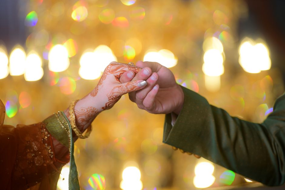 Elegant wedding moment capturing a couple's hands with henna during a ceremony.