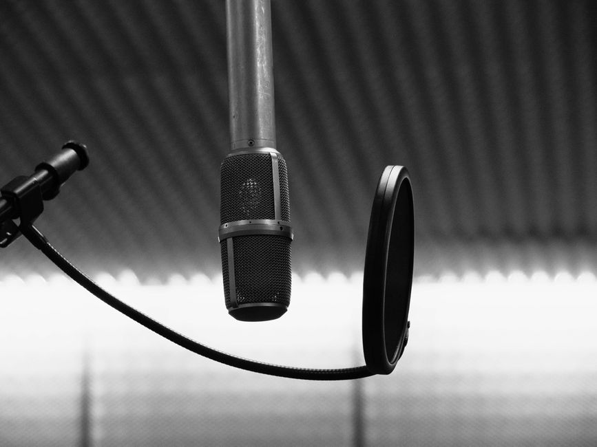 Classic black and white image of a professional studio microphone with pop filter.
