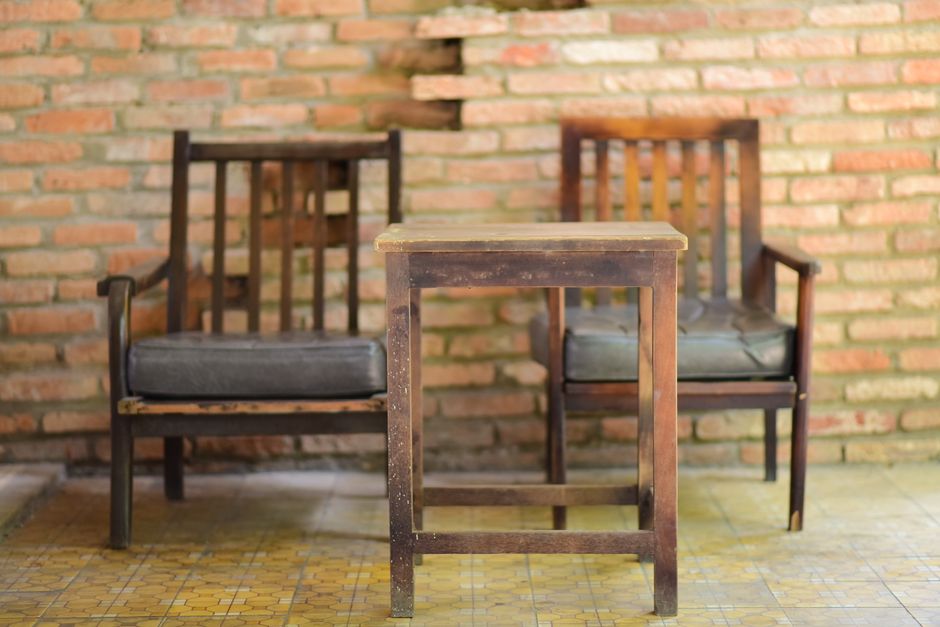 Rustic wooden chairs and table in front of a brick wall with vintage charm.