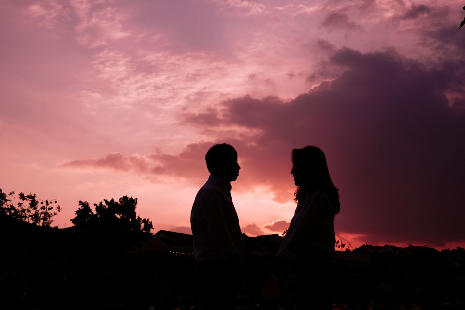 Silhouetted couple sharing an intimate moment against a vibrant sunset sky.