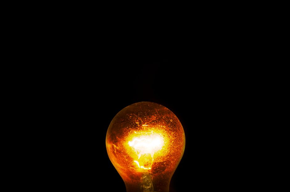 Close-up of a glowing light bulb against a dark background, symbolizing energy and innovation.