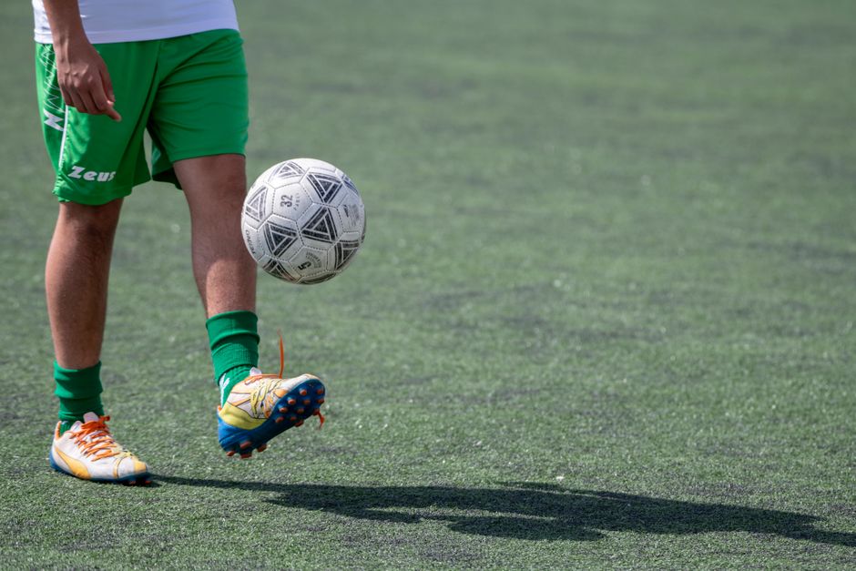 Football player practices juggling skills on a grass field. Action sports scene.