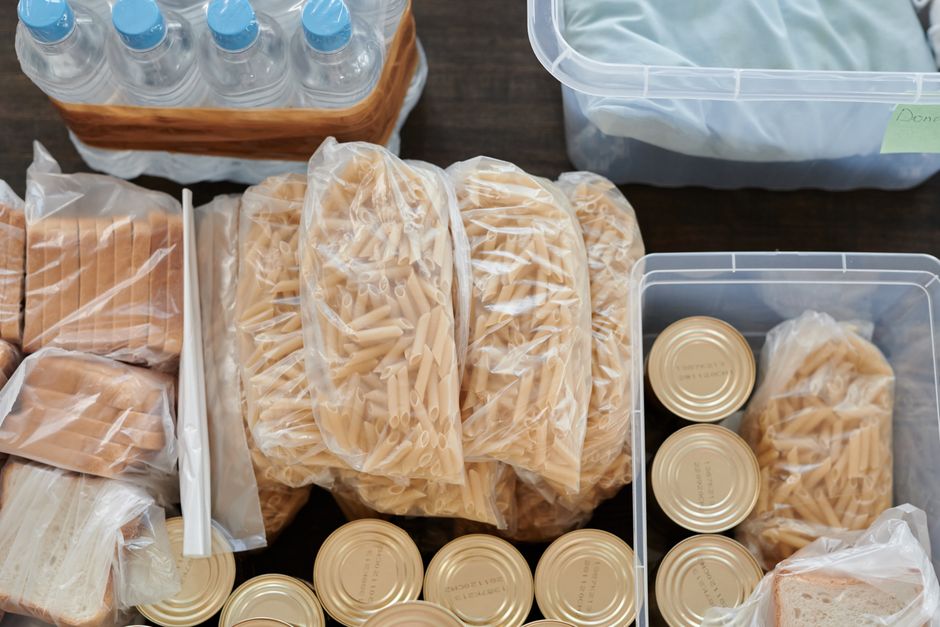 Aerial shot of pantry essentials including pasta, canned food, and bread packaged in plastic bags.