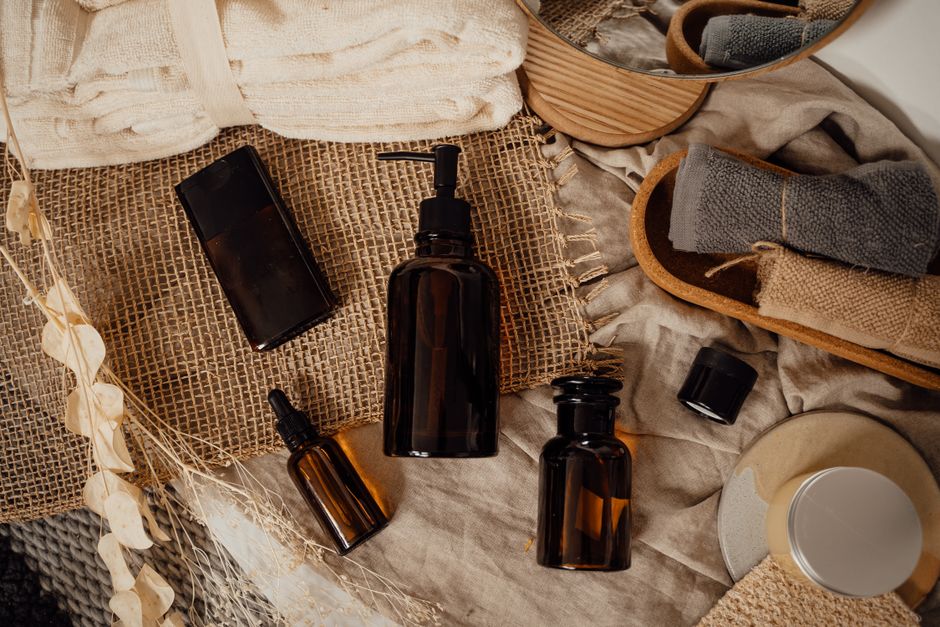 Elegant display of skincare and cosmetic bottles on a rustic background with dried flowers and towels.
