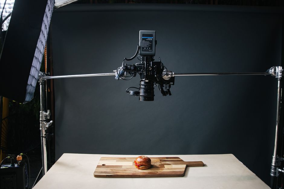 Overhead view of a food photography setup capturing a burger on a wooden board.