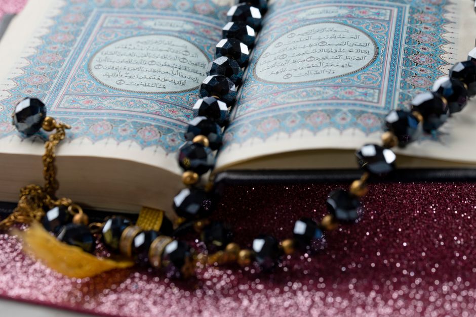 An open holy book with prayer beads resting on a sparkling surface, symbolizing serenity and spirituality.