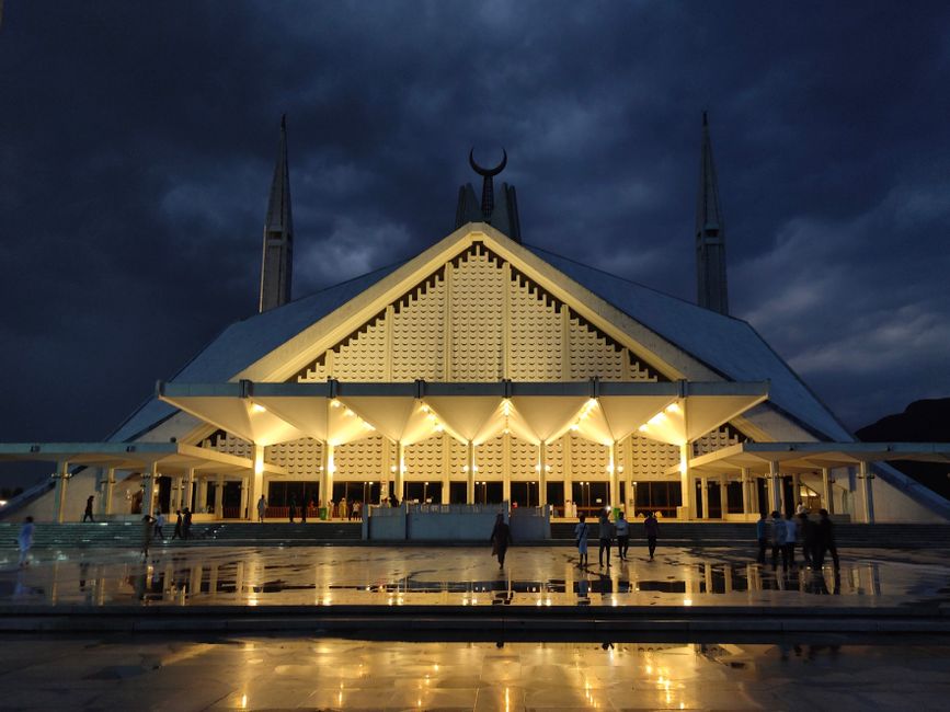 Stunning view of Faisal Mosque during blue hour in Islamabad with wet marble reflections.