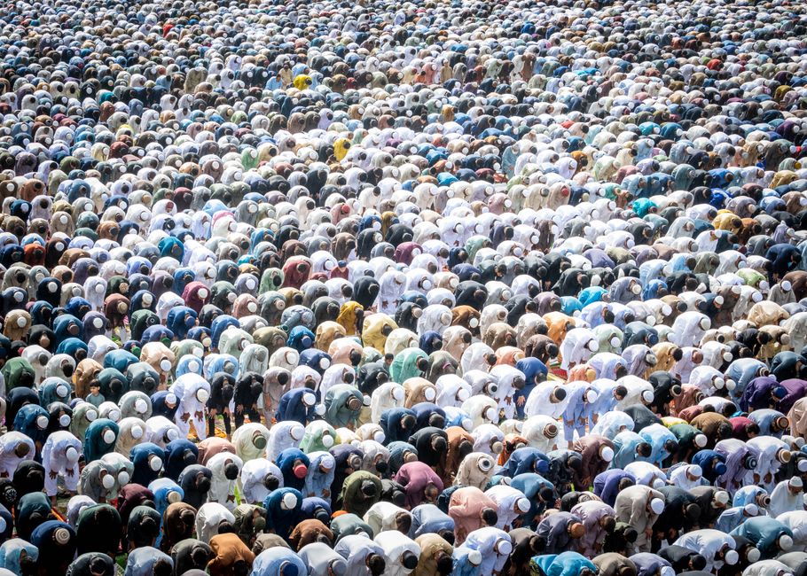 An aerial view of a large group of people bowing in prayer, showcasing unity in religious practice.