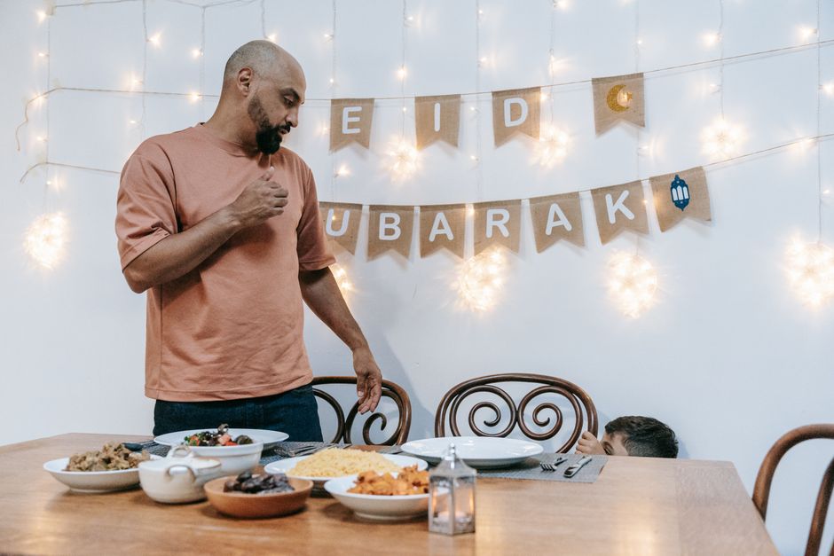 A family celebrating Eid indoors with festive meal and decorations, creating a joyful and warm atmosphere.