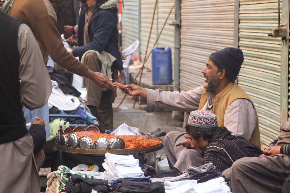 Street vendor offers traditional halwa in Mingora bazaar, Pakistan, showcasing cultural heritage.