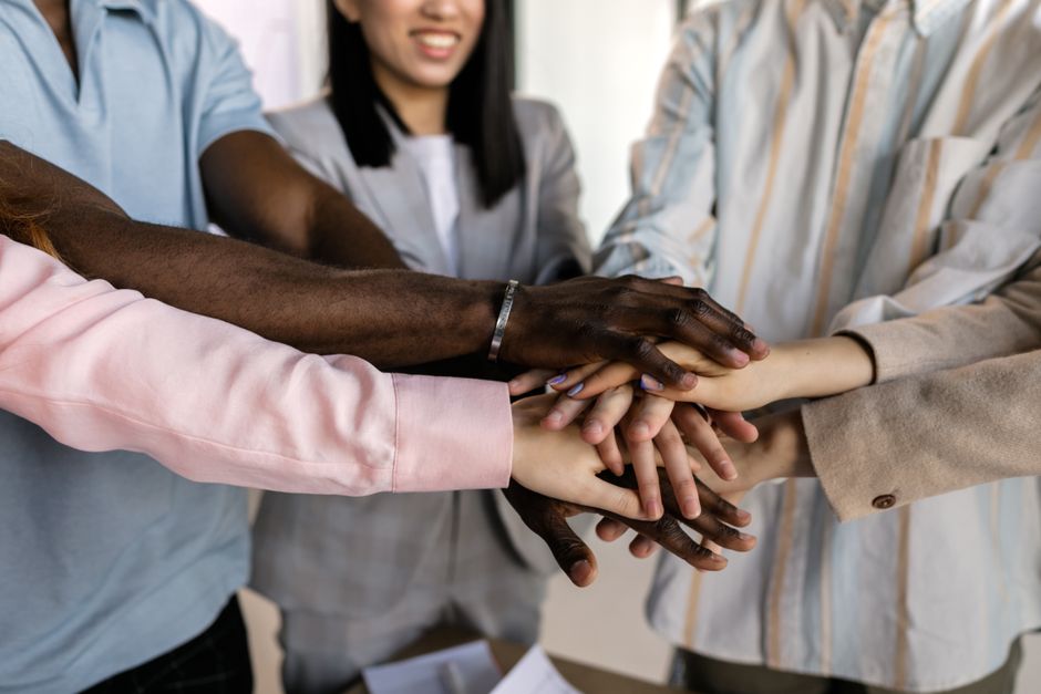 Hands of a diverse team stacked together, symbolizing unity and teamwork.