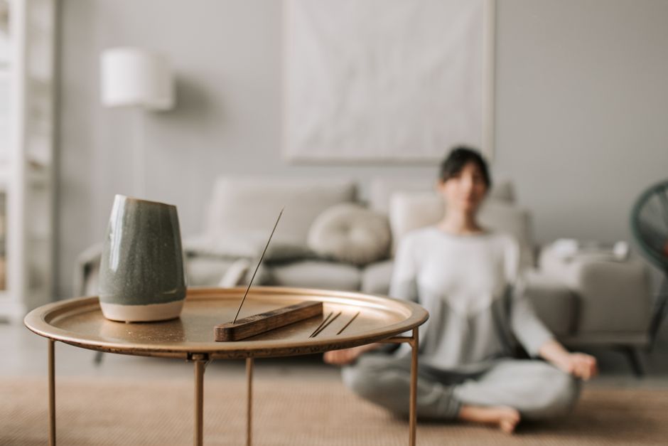 Calm living room scene with incense and a woman meditating, perfect for relaxation concepts.