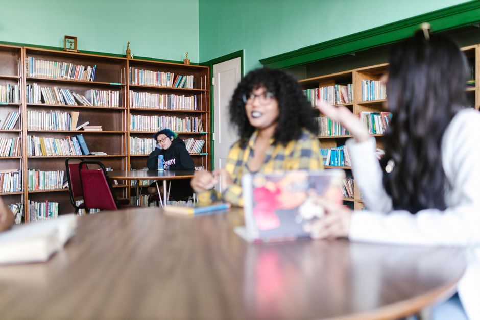 Group of students engaging in a lively discussion in a library setting, promoting education and collaboration.