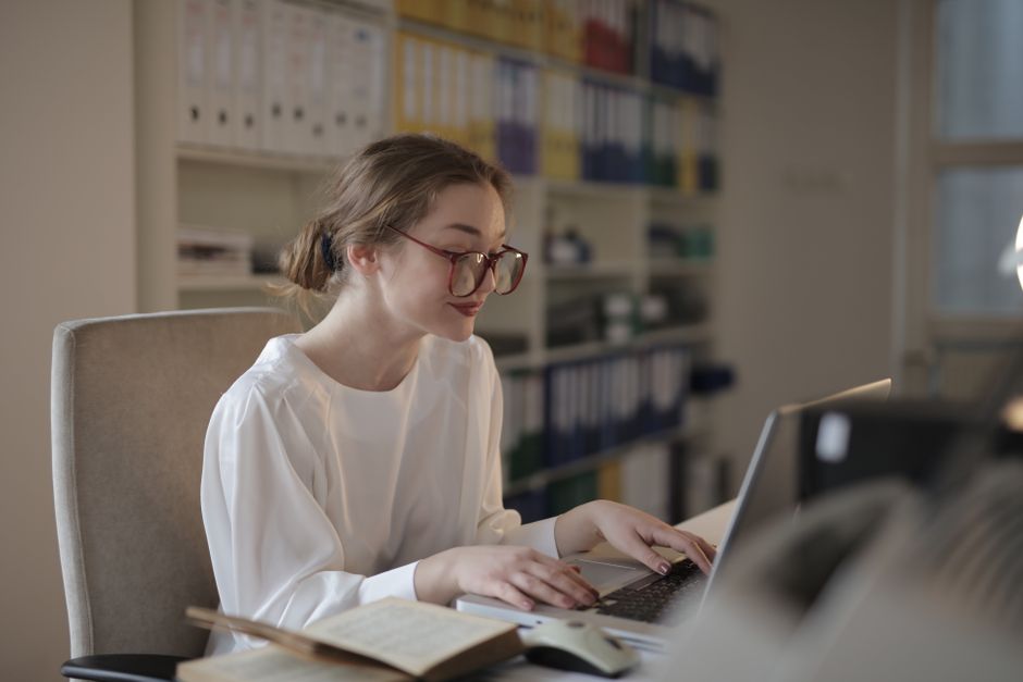 A professional woman concentrating on her laptop at a modern office desk.