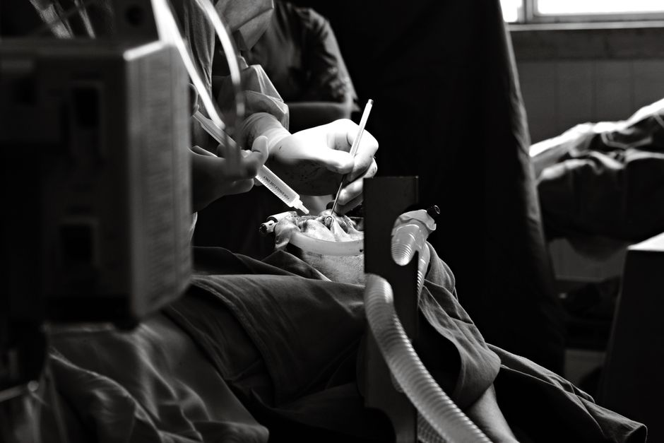 Surgeons perform a delicate procedure in a black and white scene.