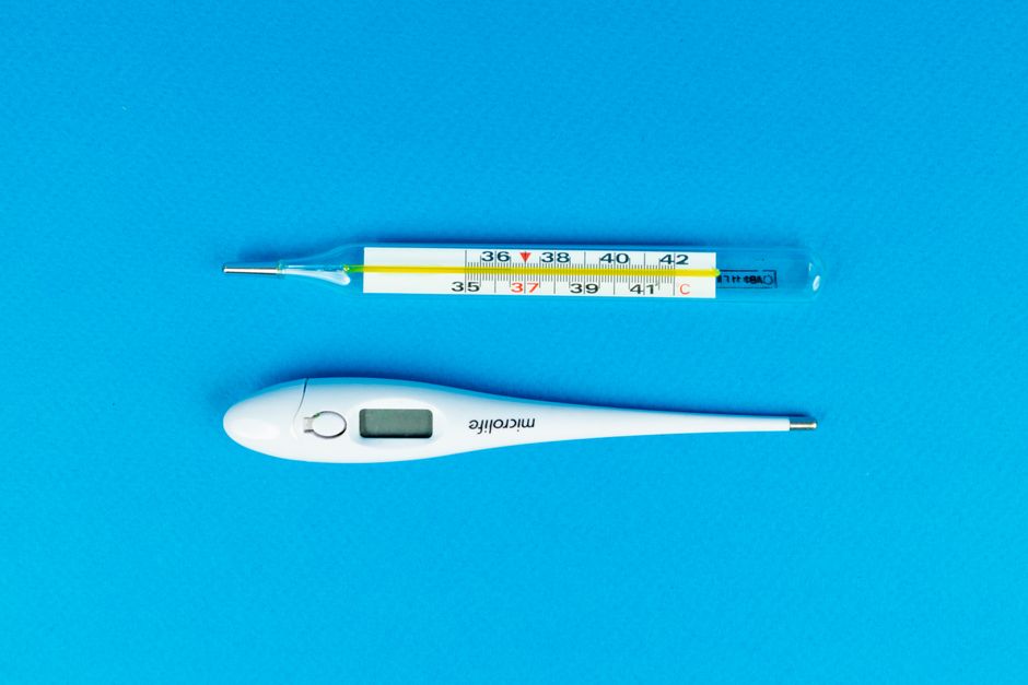 Digital and mercury thermometers on blue background for medical concept.