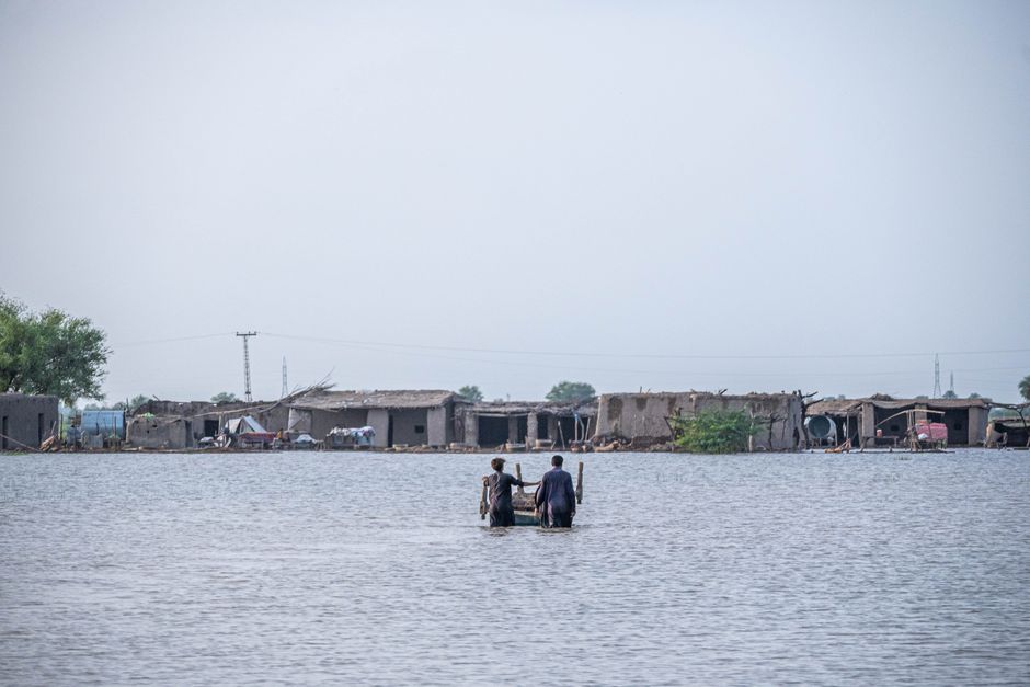 People wading through floodwaters in Gandakha City, highlighting the impact of the 2022 floods in Balochistan, Pakistan.