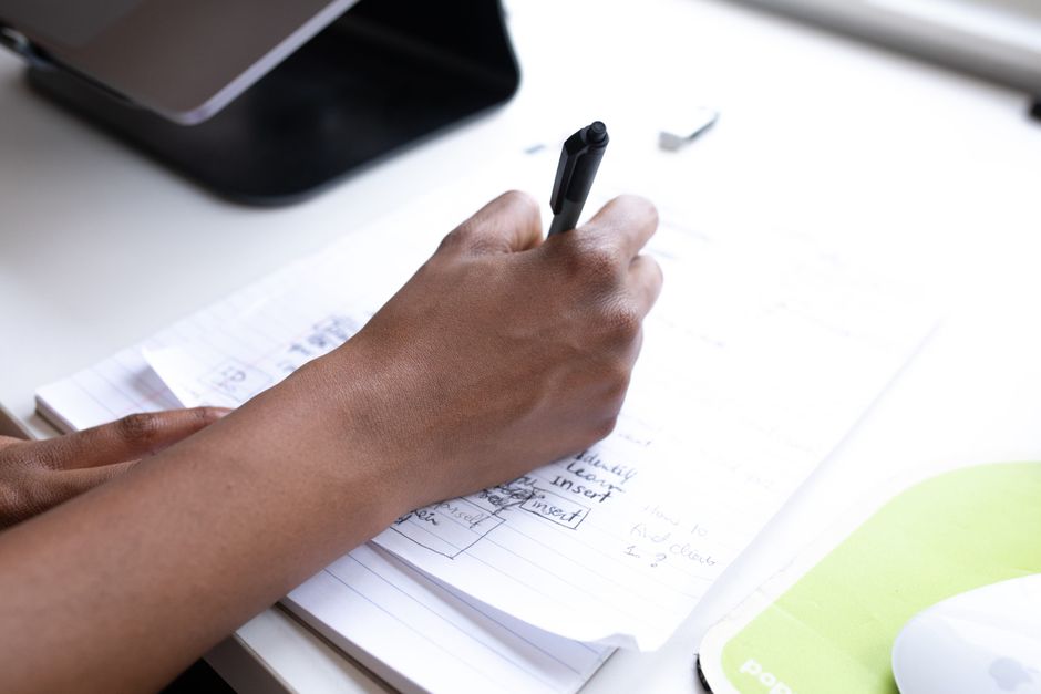 From above of crop anonymous person taking notes on papers while working at table in office