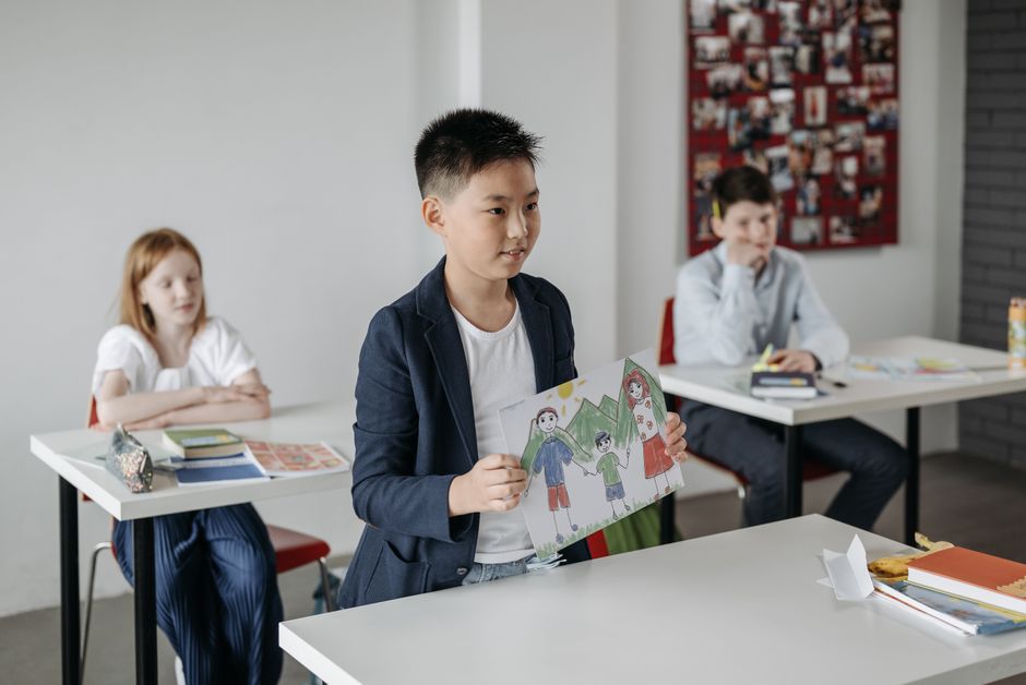 Image 1 Child showcasing drawing in a classroom setting, focusing on education.