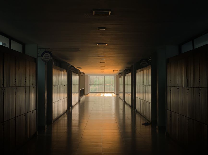Peaceful school corridor at sunset with lockers and soft lighting.
