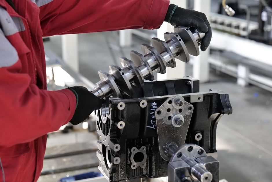 Mechanic working on a crankshaft installation in an engine block in an industrial setting.