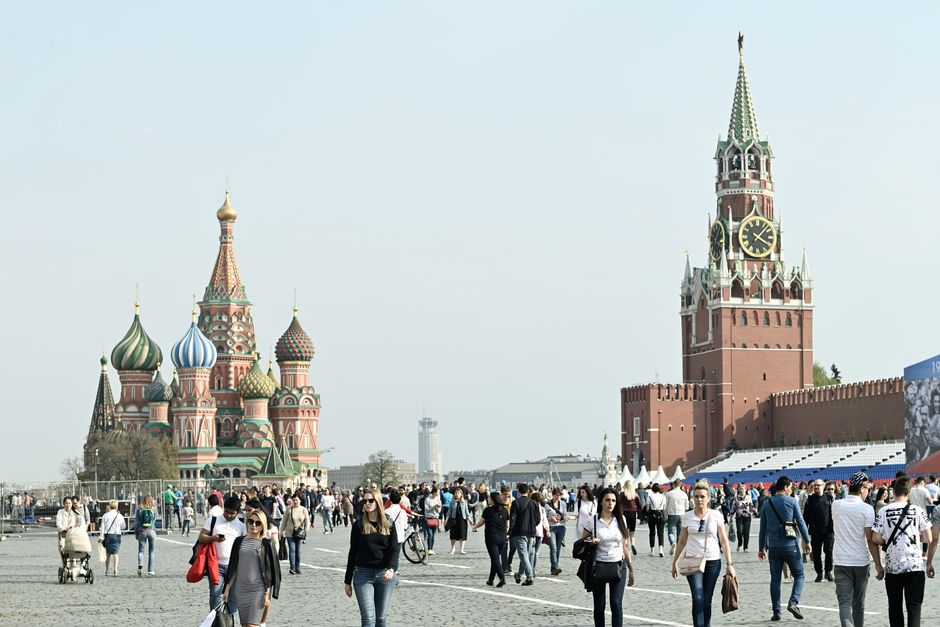Tourists gather at Moscow's iconic Red Square, featuring St. Basil's Cathedral and Spasskaya Tower.