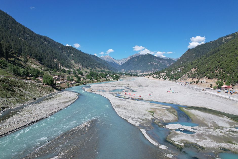 Aerial view of a beautiful river valley surrounded by mountains in Kalam, Pakistan.