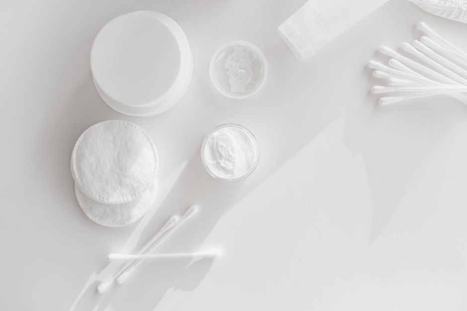 Flat lay of skincare essentials with cotton pads and cotton swabs on a white background.