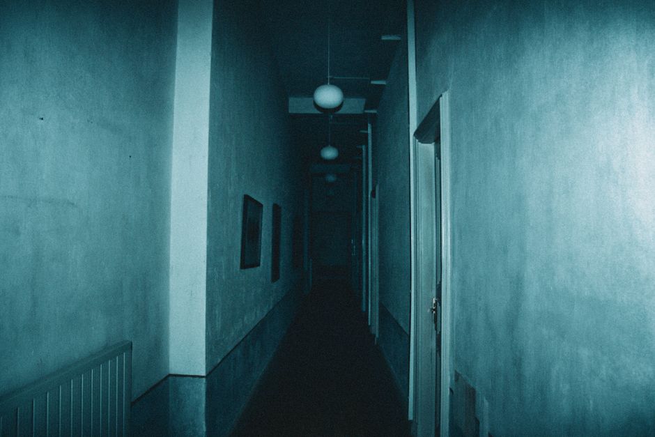 Eerie narrow hallway with dim lighting and an unsettling atmosphere.