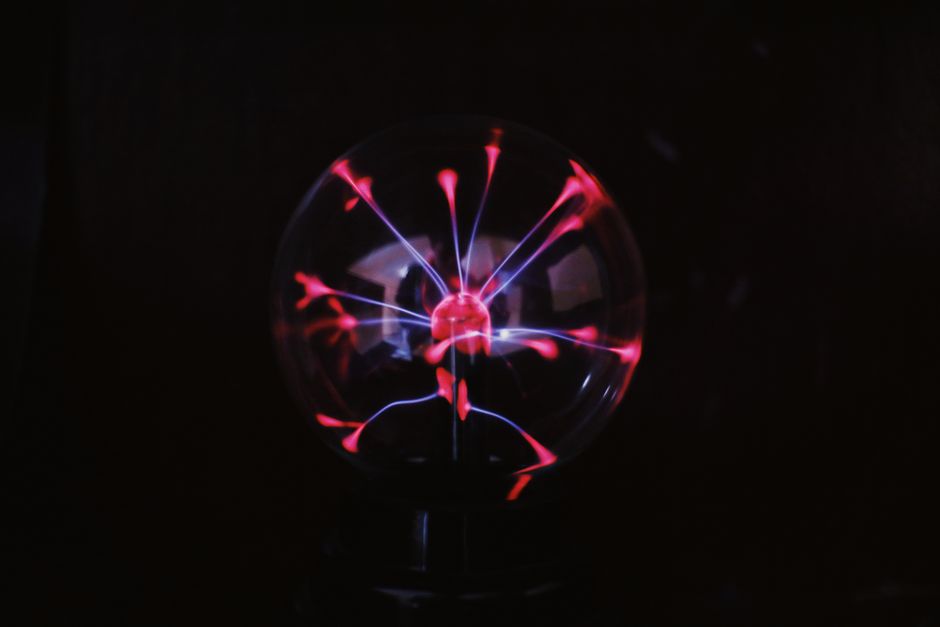 Crystal glass plasma ball with glowing electric lights inside placed in dark room