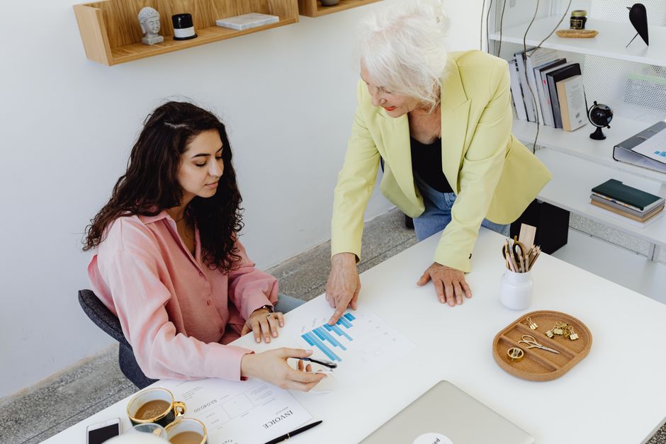 Two women analyzing business data in a modern office setting, focusing on teamwork.
