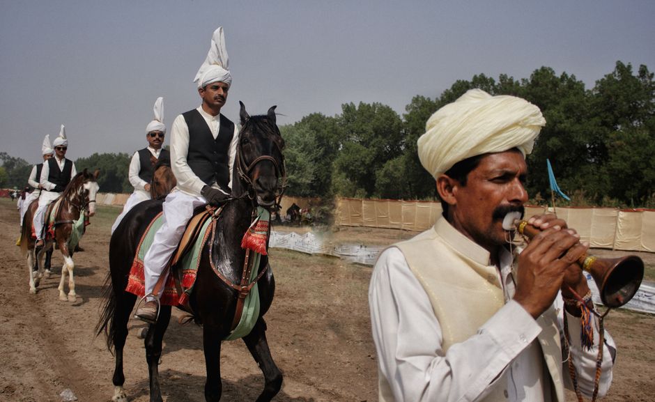 Traditional horse parade in Faisalabad with men in white turbans and traditional attire.