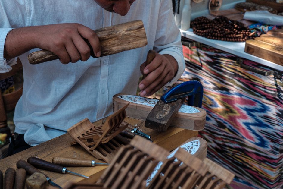 Skilled Uzbek artisan handcrafting wood carvings using traditional tools, showcasing cultural craftsmanship.
