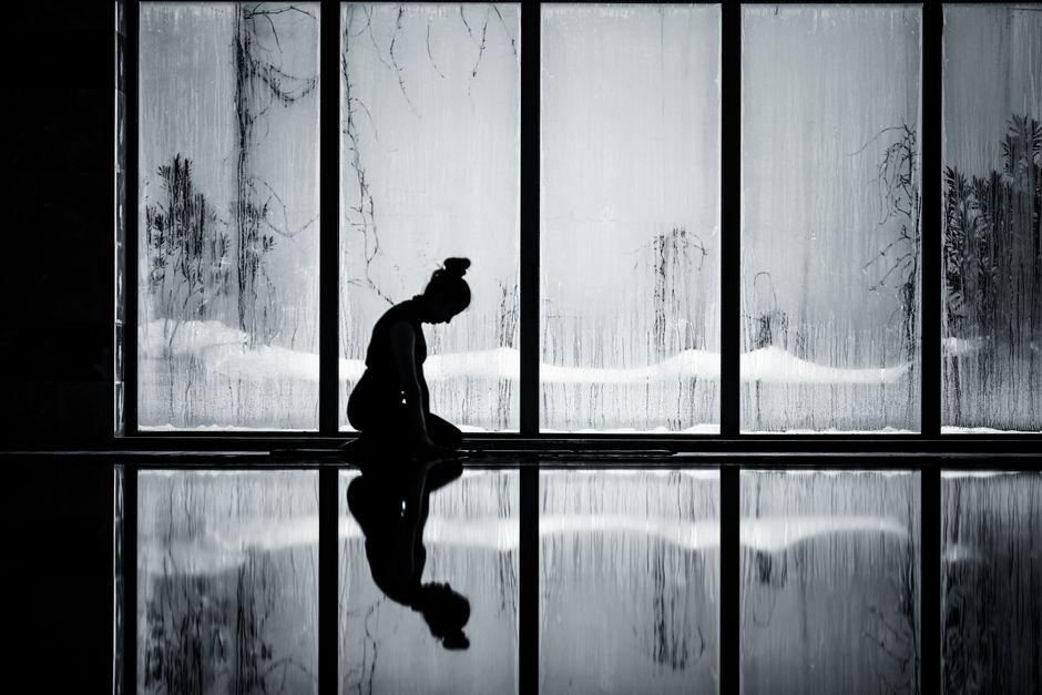 A woman kneels in meditation, silhouetted against a foggy window, reflecting tranquility.