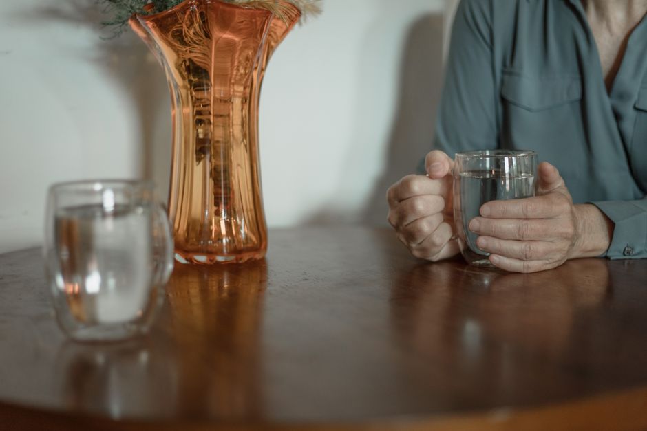 Cozy indoor scene with a person holding a glass of water, featuring an elegant vase.