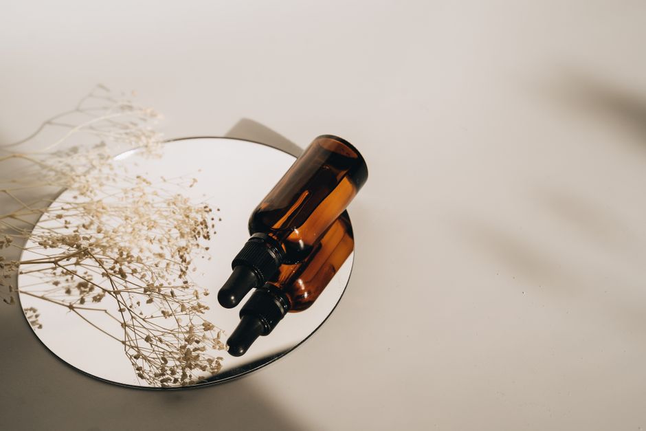 Minimalist still life with amber bottles on a mirror showcasing skincare elegance.