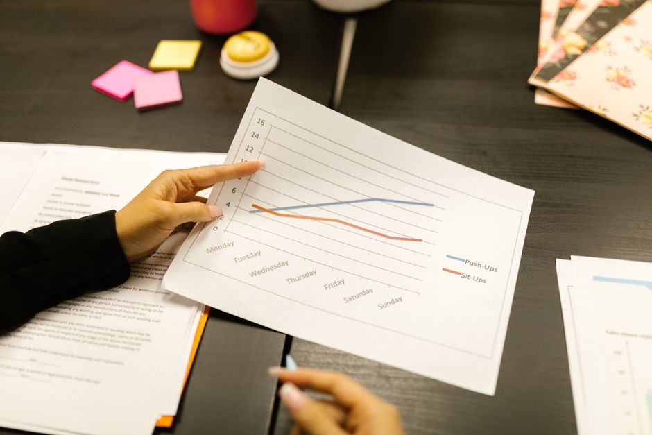 Close-up of hands analyzing a graph during an office meeting, highlighting fitness progress.