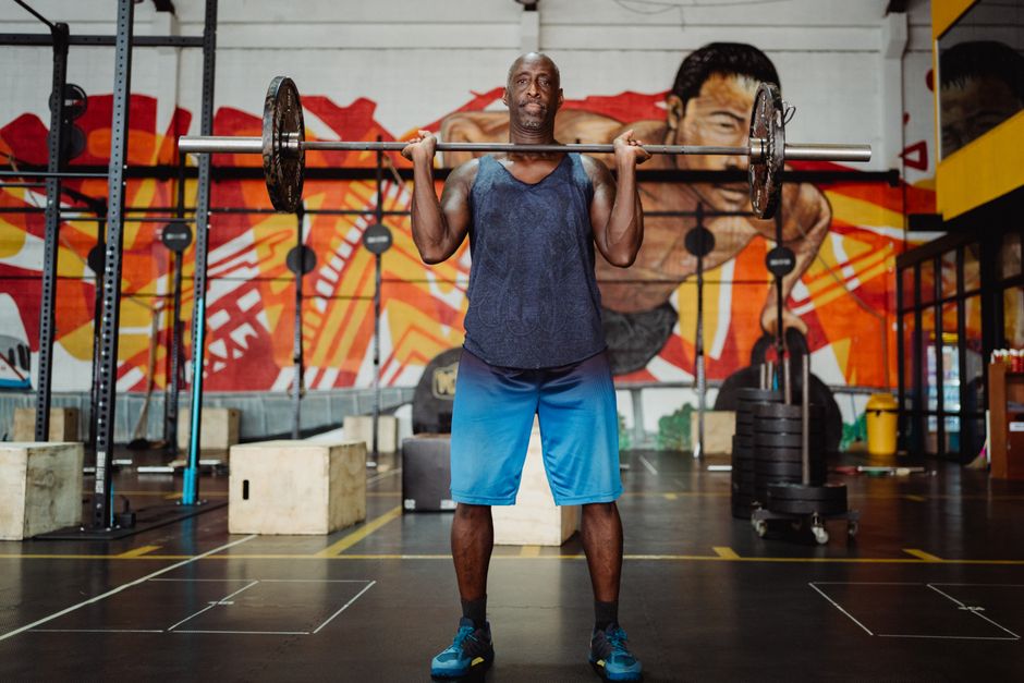 Athletic man lifting weights in a colorful gym setting, showcasing strength and fitness.