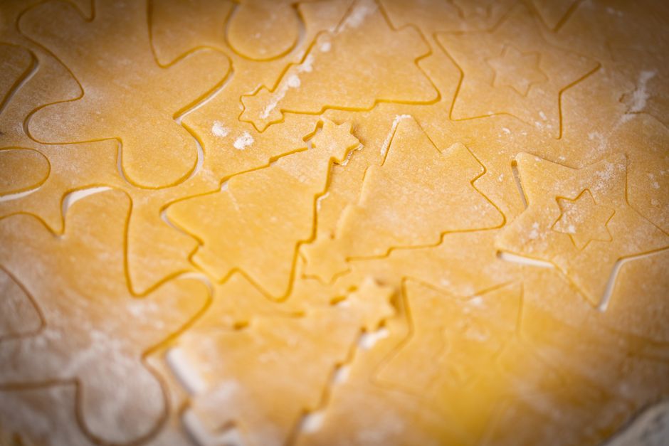 Festive cookie dough rolled out with Christmas shapes for baking.